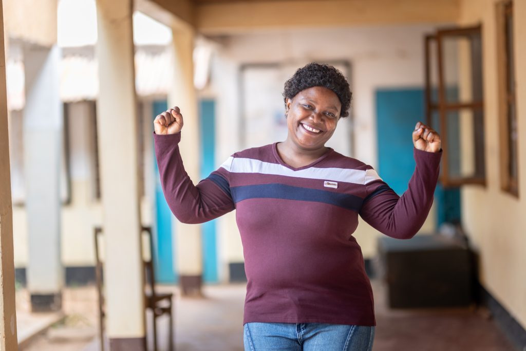 Stumai stands and smiles in a classroom in Tanzania