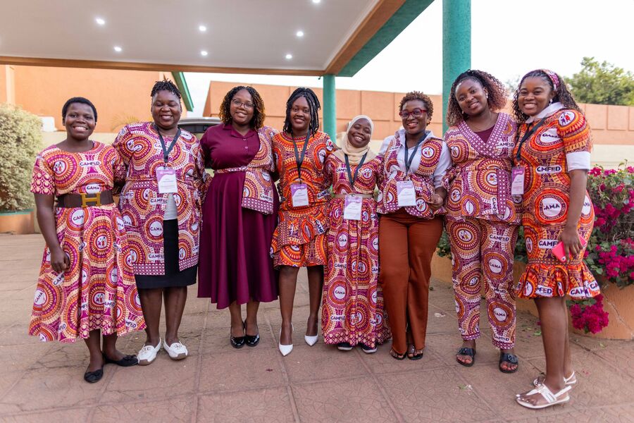 A group of women wearing bright, patterned dresses and standing outside a building.